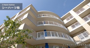 介護施設の建物外観。曲線的なデザインの5階建て施設。バルコニーが特徴的。